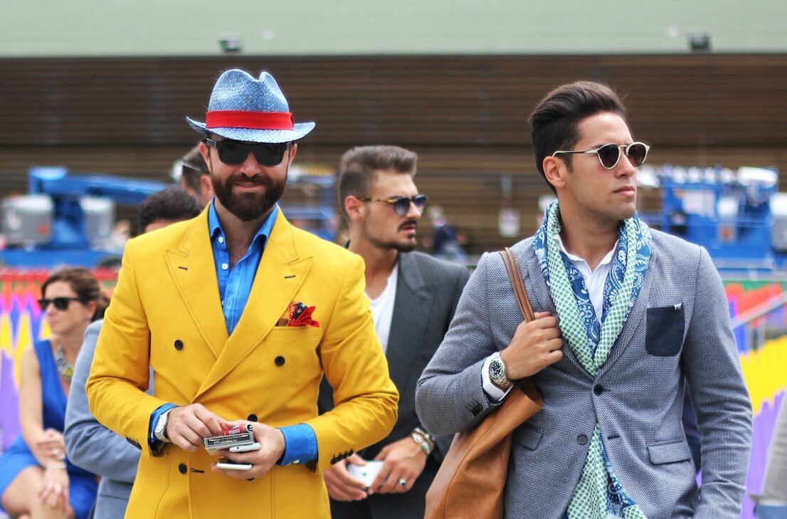 two man wearing yellow and grey suit jacket standing close together