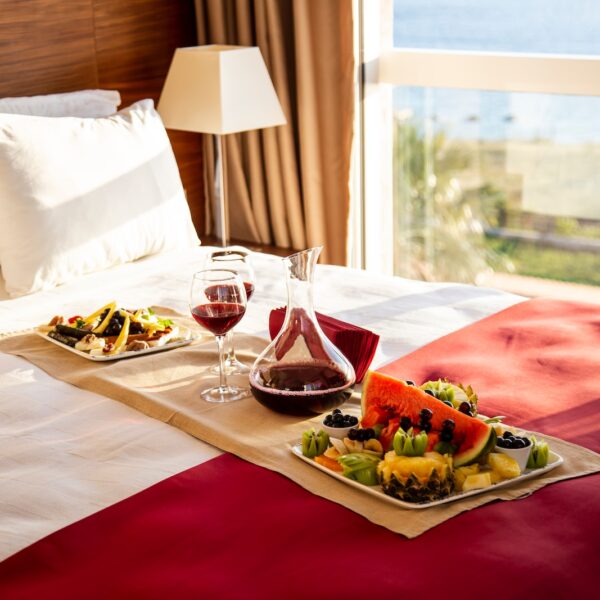 vegetable salad on white ceramic plate beside wine glass on red table cloth