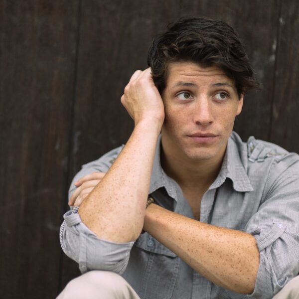 man wearing gray dress shirt leaning on brown wall