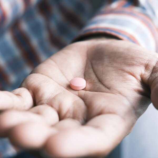 person holding pink round medication pill