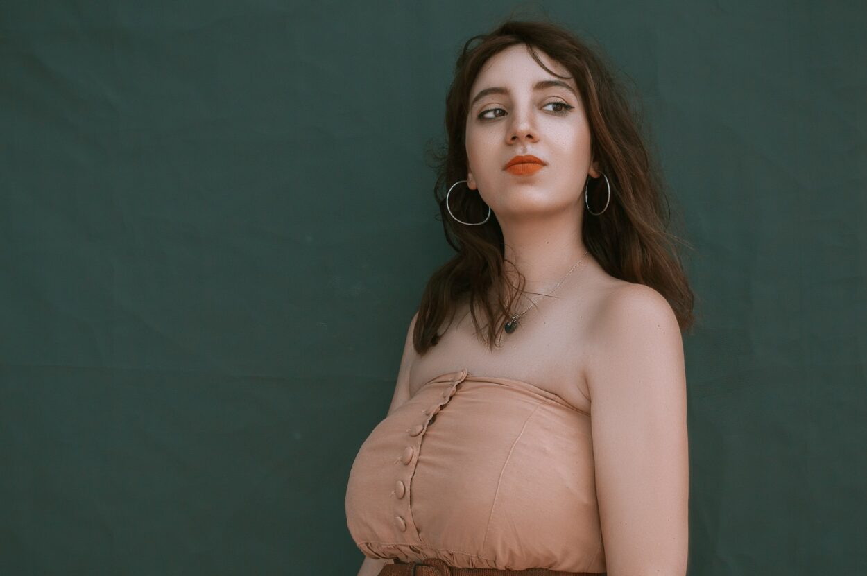 woman in brown top beside wall